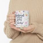 Woman in a cream sweater holding the Retired and Just Getting Started watercolor floral mug