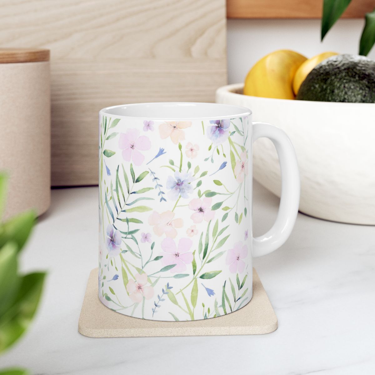 Watercolor floral ceramic mug on a coaster in a kitchen with a bowl of lemons